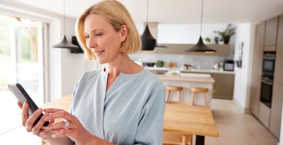 Homeowner holding a cell phone in a room filled with sunlight